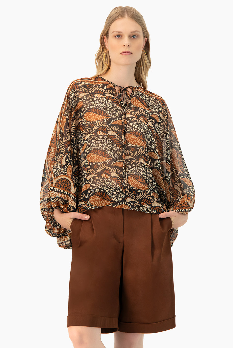 Blusa estampada café con cintas en cuello y mangas murciélago.