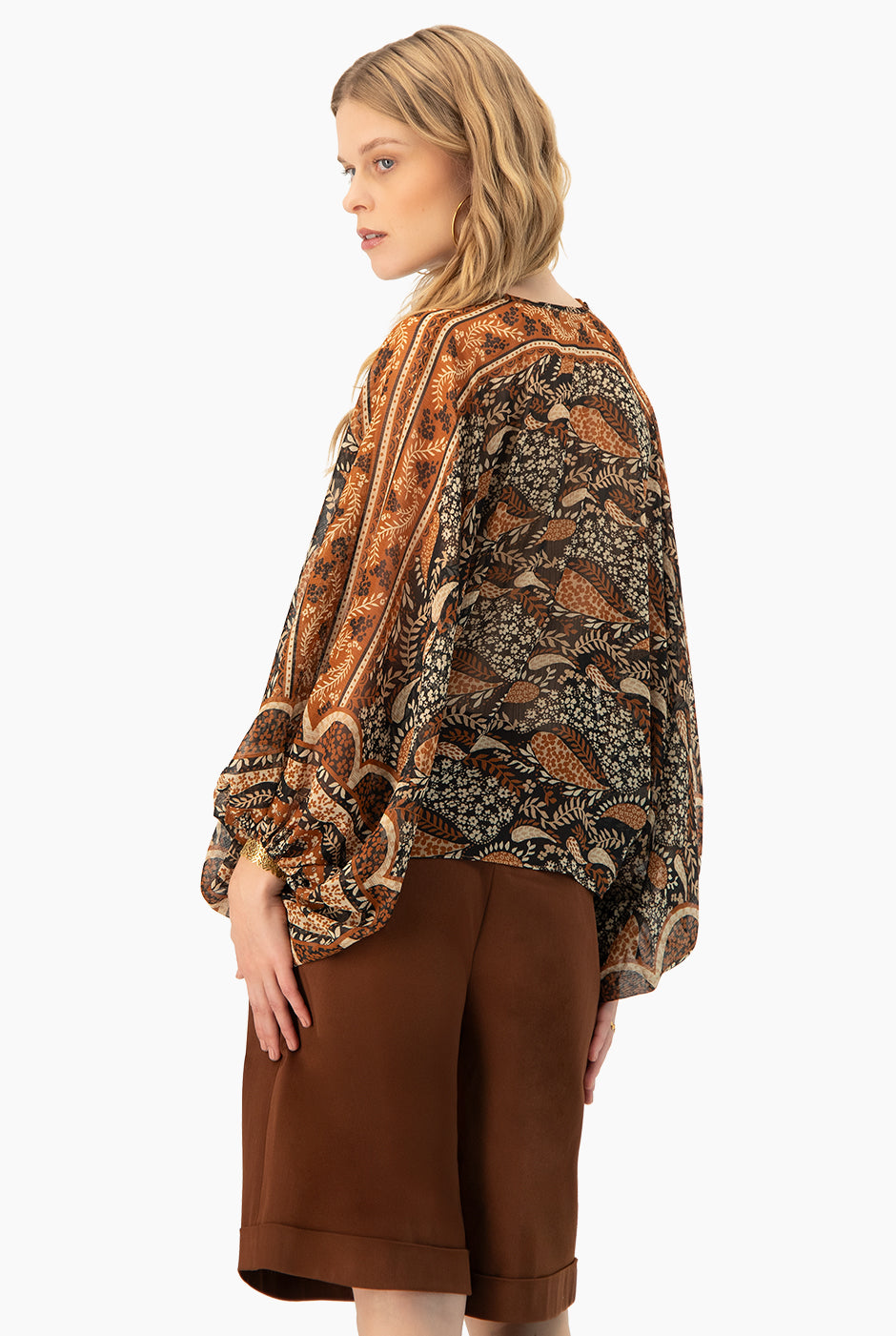 Blusa estampada café con cintas en cuello y mangas murciélago.