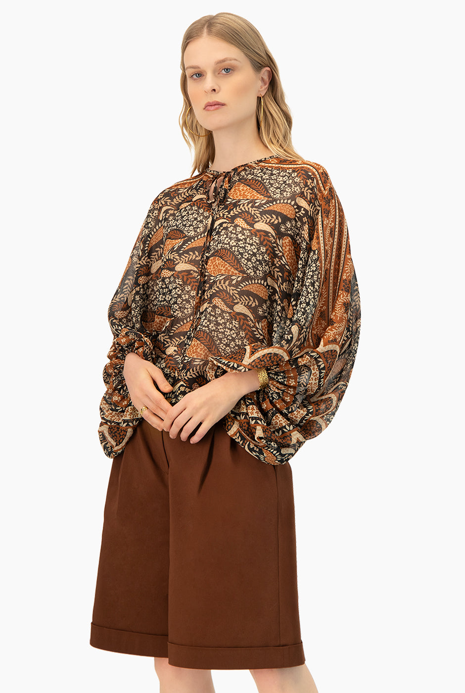 Blusa estampada café con cintas en cuello y mangas murciélago.