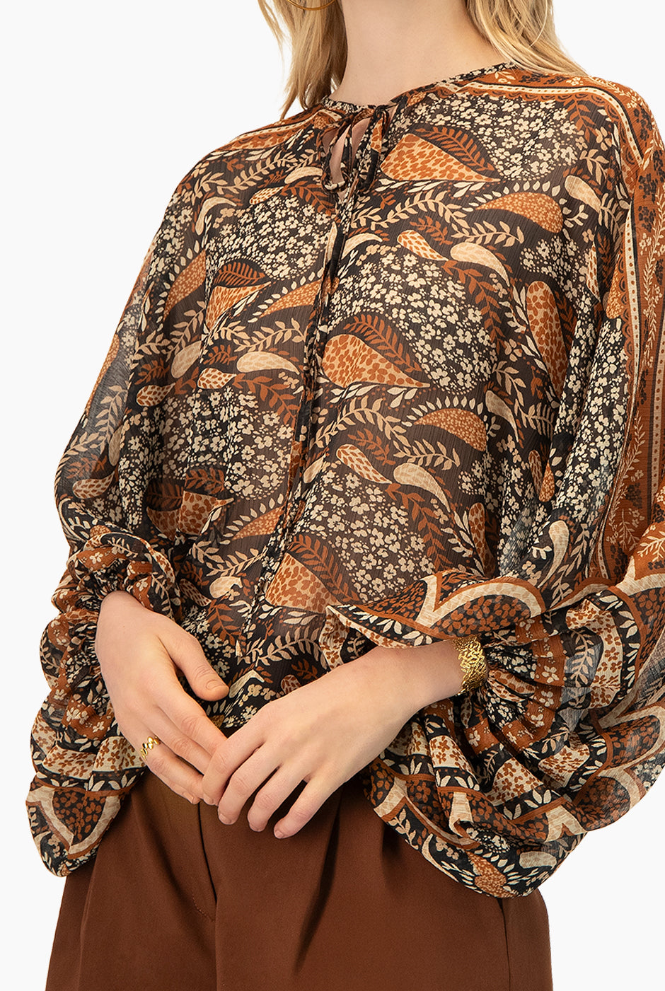 Blusa estampada café con cintas en cuello y mangas murciélago.